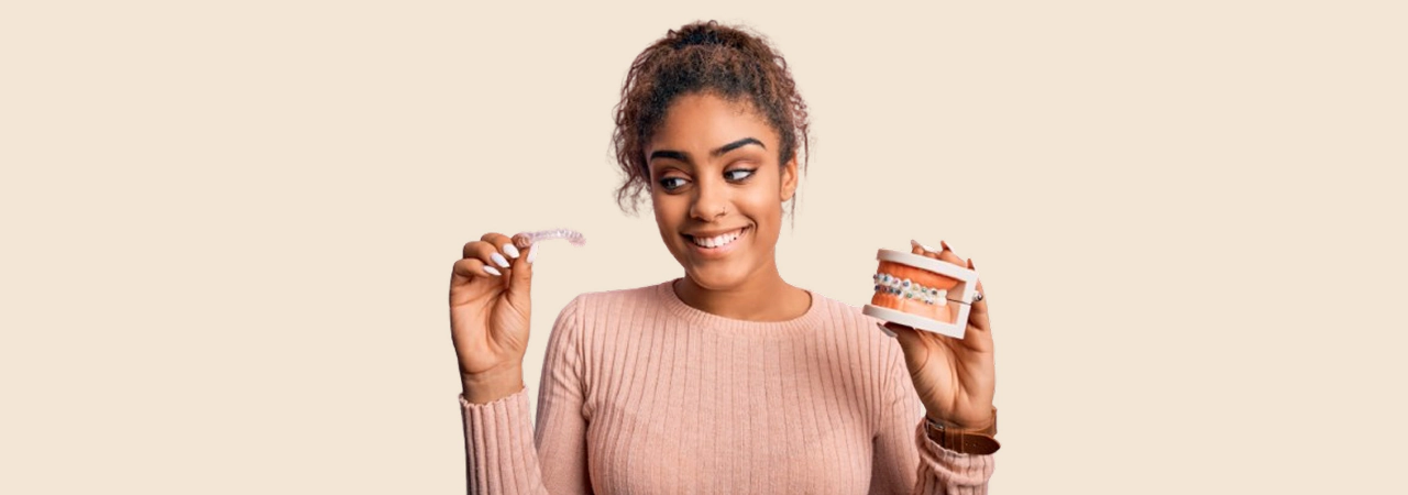 Smiling woman holding a clear aligner and braces model, clear aligners in Palatine, IL