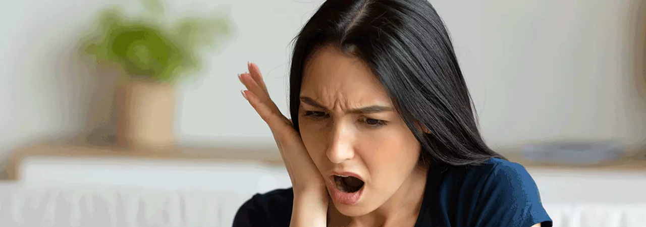 Woman holding her cheek in pain, needing emergency dental care