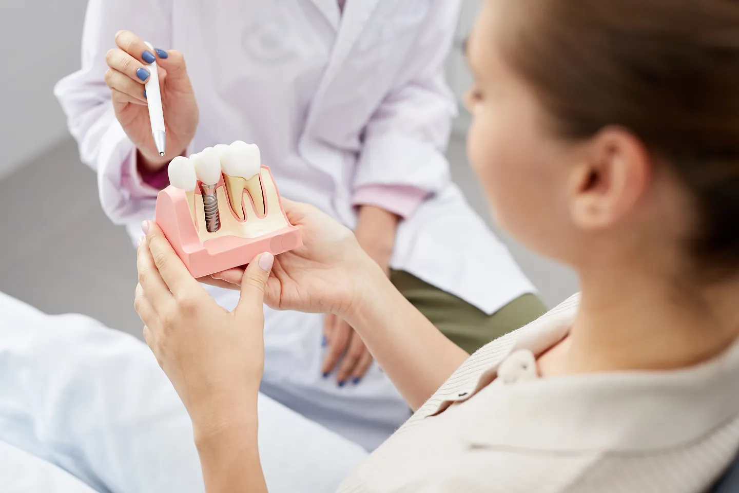 Dentist showing a patient a model of a dental implant