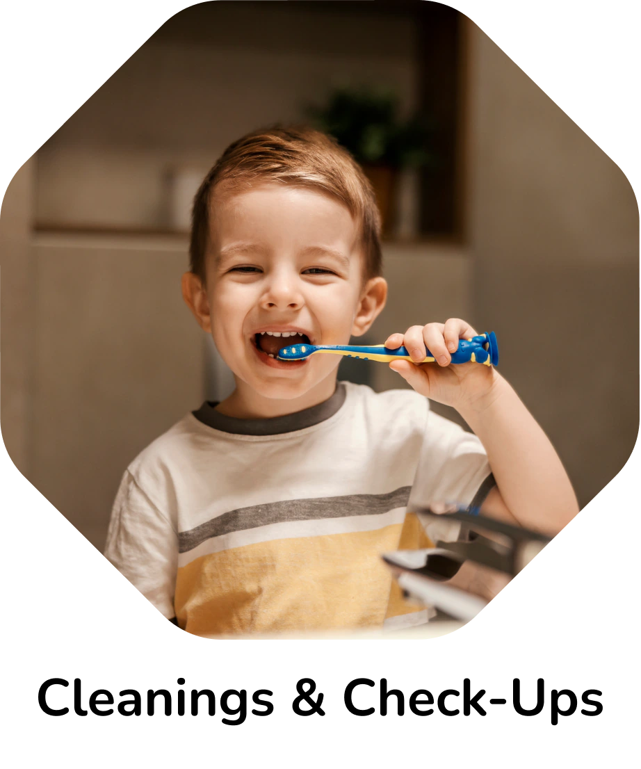Cleanings & Check-Ups – young boy smiling while brushing his teeth