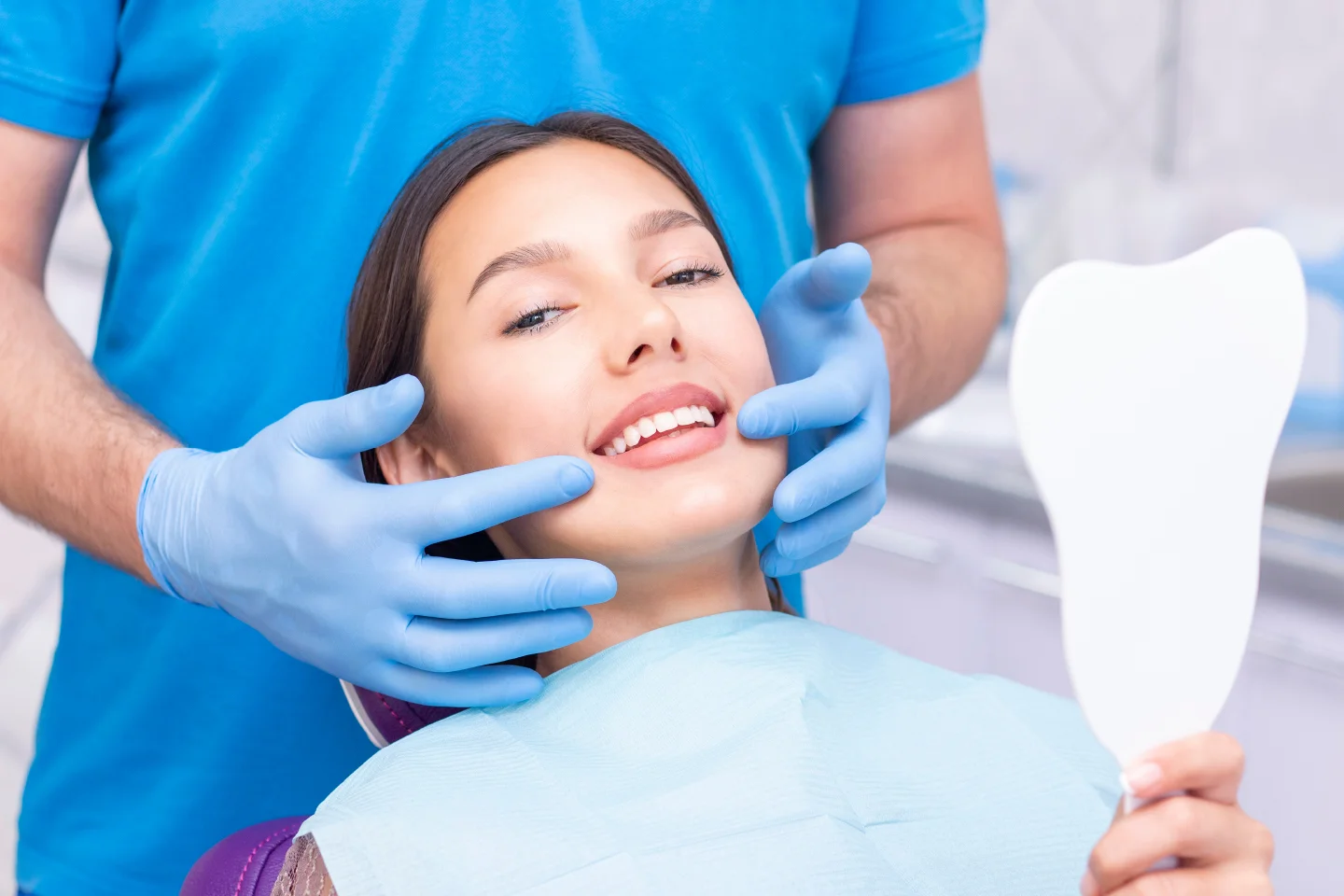Dentist examining a smiling woman’s teeth during a cosmetic consultation